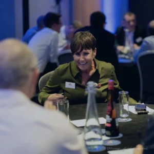 Employer brand. A woman engaged in a conference breakout session sat at a table at a corporate event.